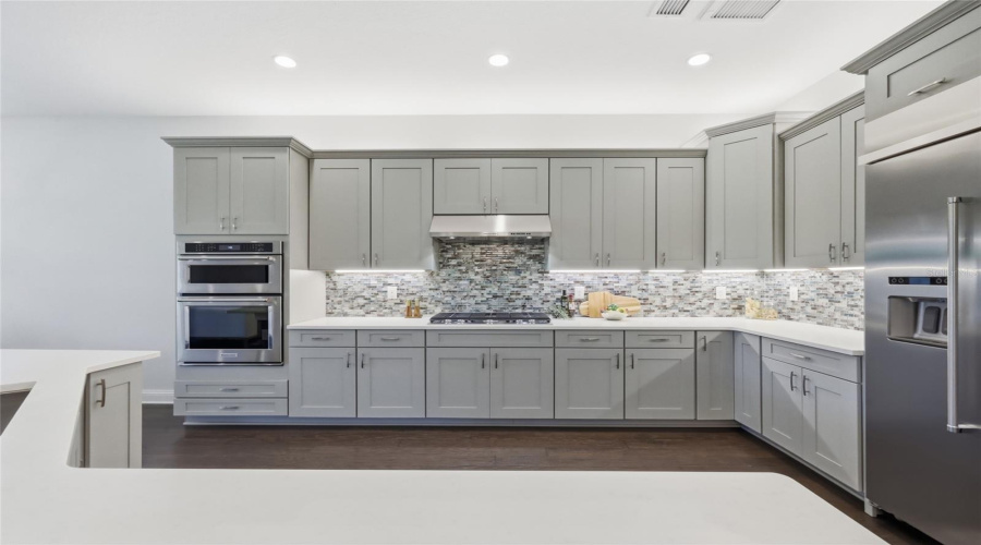 Thoughtfully Designed  Kitchen with Quartz Counter tops, Glass Backsplash, Upgraded Natural Gas Range, Upgraded Cabinets, and Oversized Island