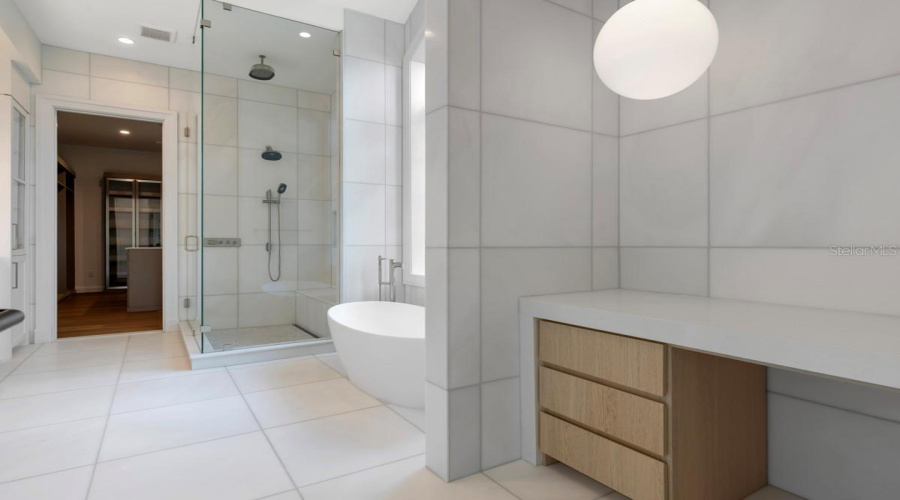 Indulgent primary bath features a freestanding tub, along withcustom vanities, marble floors, walls and shower with full-length shower bench and niche
