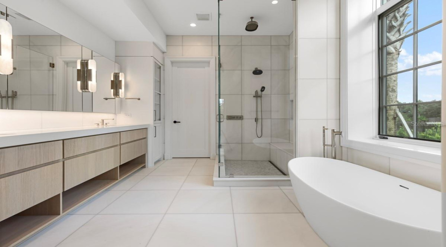 Indulgent primary bath features a freestanding tub, along withcustom vanities, marble floors, walls and shower with full-length shower bench and niche