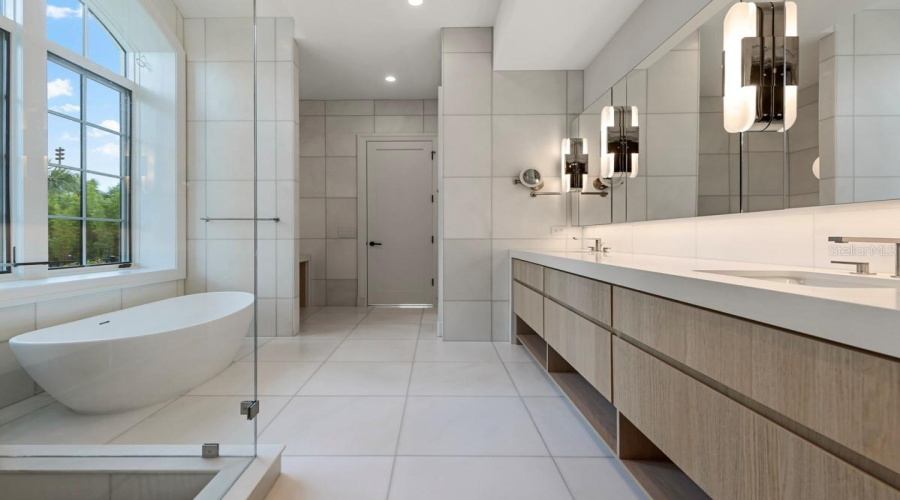 Indulgent primary bath features a freestanding tub, along withcustom vanities, marble floors, walls and shower with full-length shower bench and niche