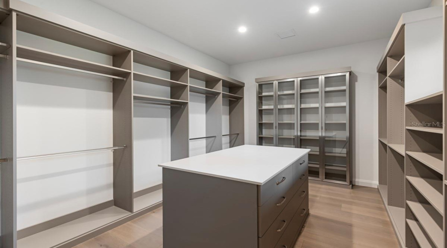 Expansive walk-incloset with stone-topped island and custom storage system