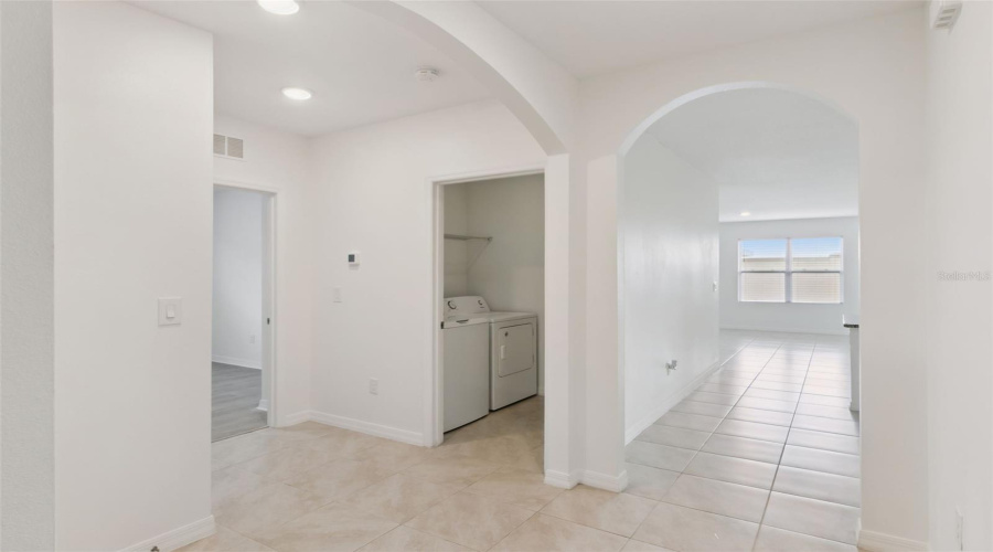 Hallway & Laundry Area:Central hallway with durable tile flooring and arched pass-throughs, complete with a dedicated laundry closet equipped with a washer and dryer.
