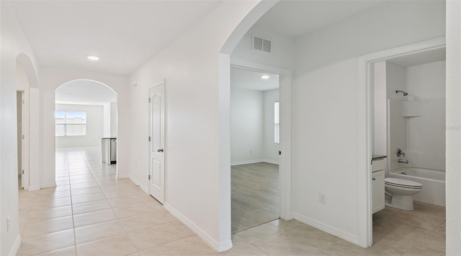 Hallway & Guest Bathroom:Flowing interior layout featuring low-maintenance tile throughout, leading to guest bedrooms and a full secondary bathroom with a tub/shower combo.