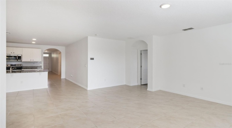 Great Room & Kitchen Bar:Vast main living room perfect for entertaining, with seamless flow into the kitchen bar seating area, tile backsplash, and sleek recessed lighting.