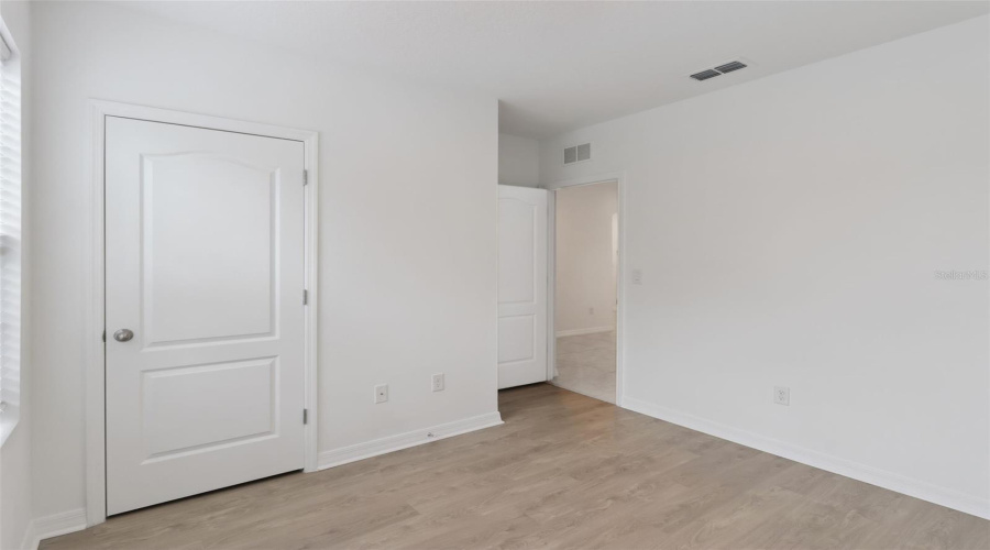Bedroom Interior:Bright secondary bedroom featuring low-maintenance wood-look plank flooring, crisp white walls, and a private closet.
