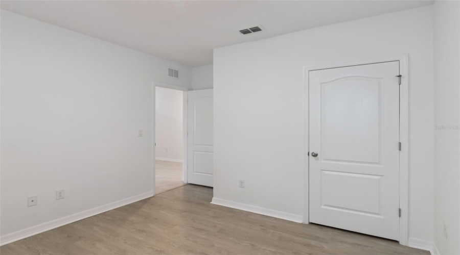 Bedroom Doorway & Closet:Versatile bedroom space complete with durable wood-look plank flooring, neutral paint, dedicated closet, and seamless access to hallway transitions.