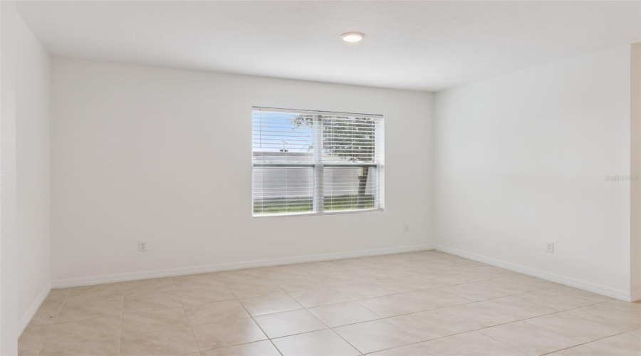 Versatile Tiled Space / Bedroom:Flexible room featuring continuous neutral tile flooring, flush-mount lighting, and a bright window with blinds.