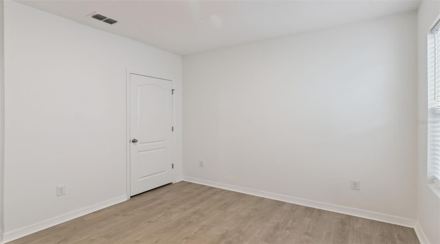 Bedroom Corner:Versatile guest bedroom or home office space complete with modern wood-look flooring, neutral trim, and a full-size closet.
