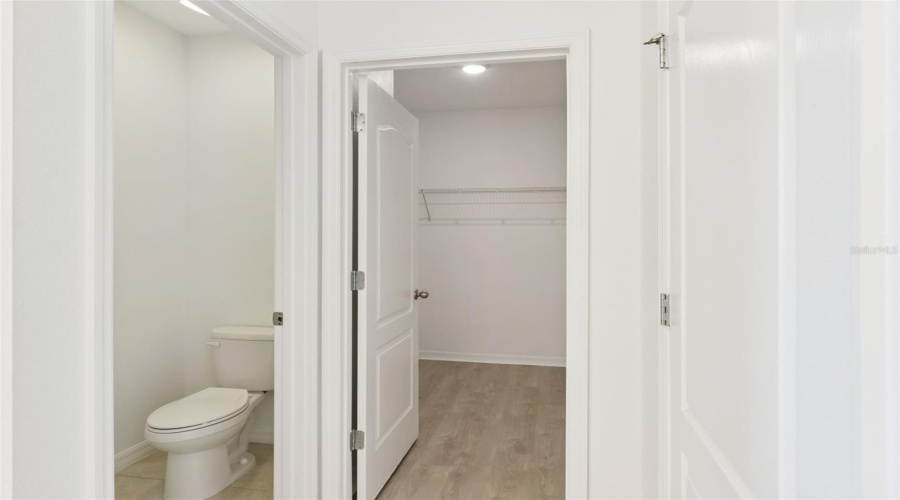 Water Closet & Walk-In Closet:Functional en-suite layout showcasing a private water closet separate from a generous walk-in closet equipped with built-in wire shelving.