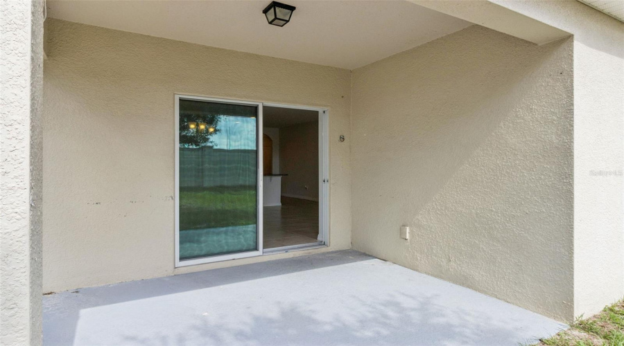 Covered Patio & Sliding Entry:Private covered concrete patio featuring smooth stucco finishes, exterior lighting, and direct sliding glass door entry into the main home.
