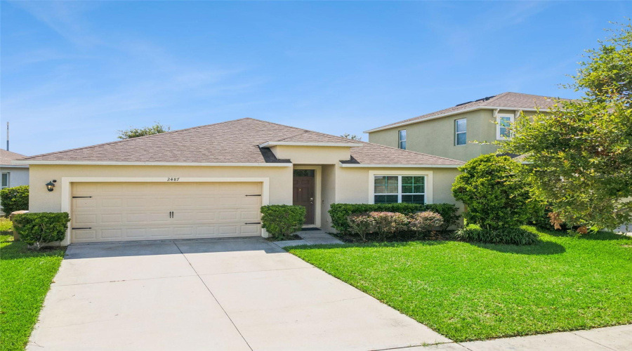 ront Yard & Driveway:Wide front view highlighting the spacious driveway, manicured green lawn, mature foliage, and inviting covered entryway.