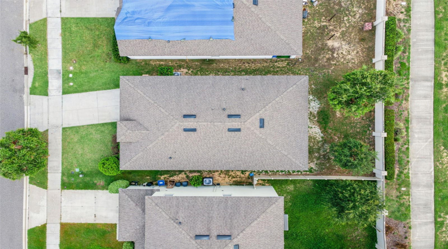 Aerial Top-Down Lot View:Direct overhead drone view illustrating the full lot footprint, shingle roof condition, front driveway, and private back yard layout.
