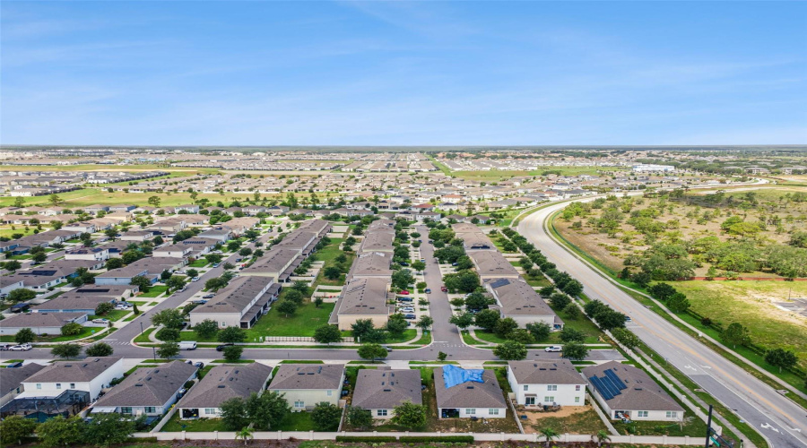 Neighborhood Streetscape:High-altitude aerial view showcasing the quiet neighborhood street layout, well-maintained homes, and convenient proximity to surrounding open green space and local roadways.