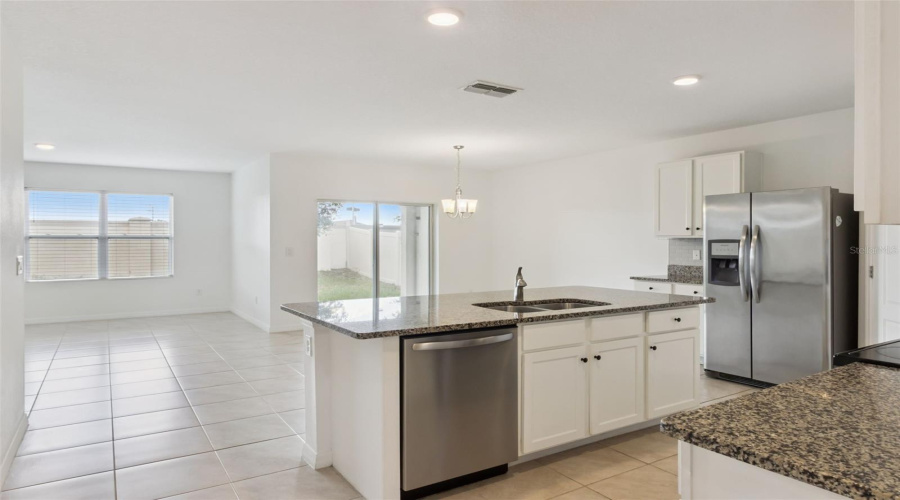 Island Prep & Dishwasher View:Central kitchen island featuring an integrated stainless steel dishwasher, ample prep space, and an open view into the primary living and dining areas.