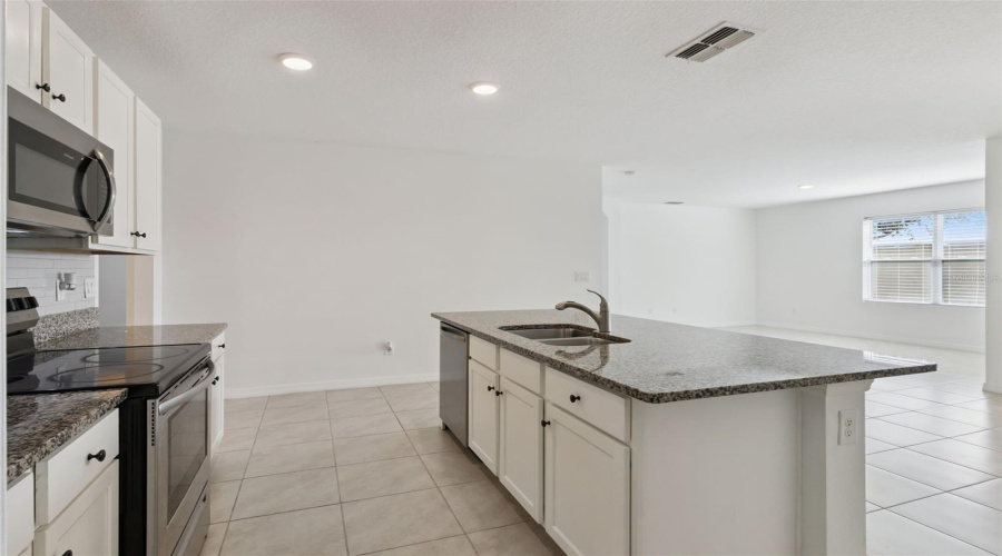 Kitchen Island & Sink:Functional island equipped with an undermount double-basin stainless steel sink, pull-down faucet, granite counter space, and clear sightlines across the home.