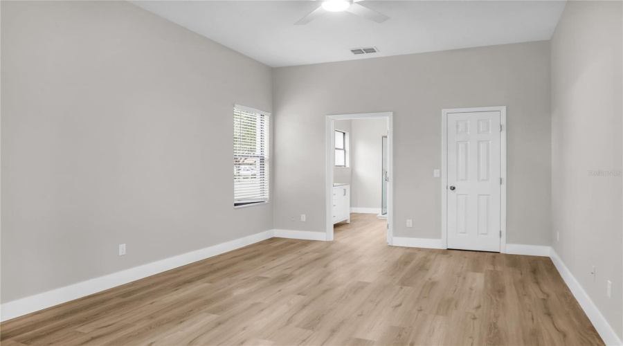 First Floor Primary Bedroom with walk-in closet, slider doors leading to covered lanai