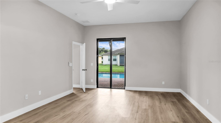 First Floor Primary Bedroom with walk-in closet, slider doors leading to covered lanai