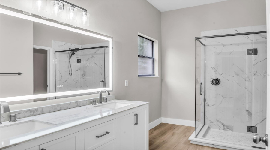Fully redesigned First Floor Primary Bath features a double quartz vanity with anti-fog LED light up mirror and glass enclosed walk in tile shower.