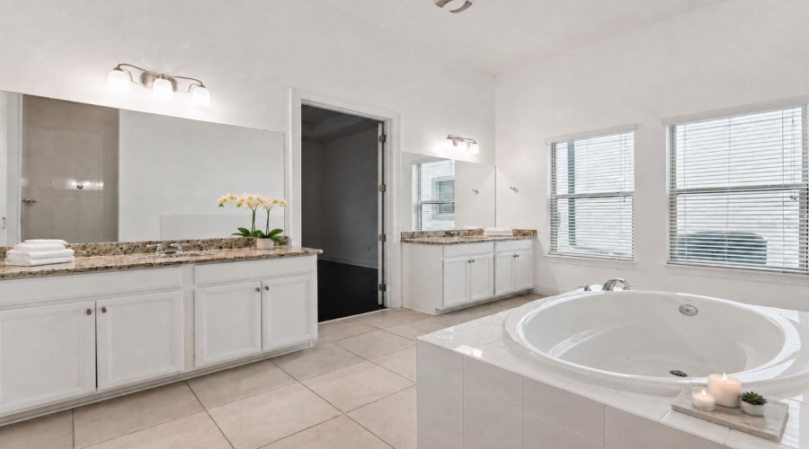 Spacious primary bathroom completed with two vanities, a tub and shower