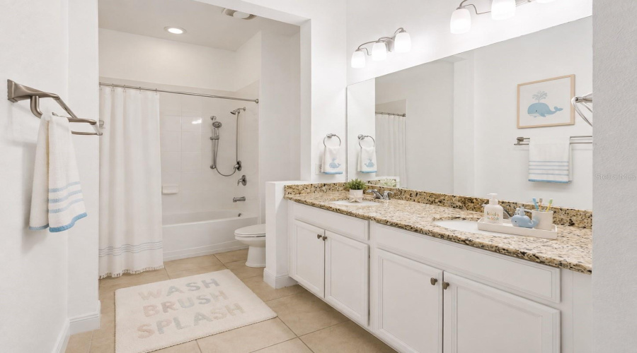 Shared bathroom for bedroom 3 and 4 with dual vanities and a tub