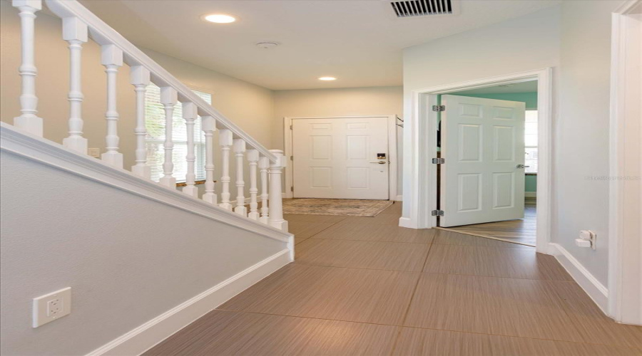Welcoming Foyer Entry With Modern Tile Flooring And High Ceilings Creating An Inviting First Impression.