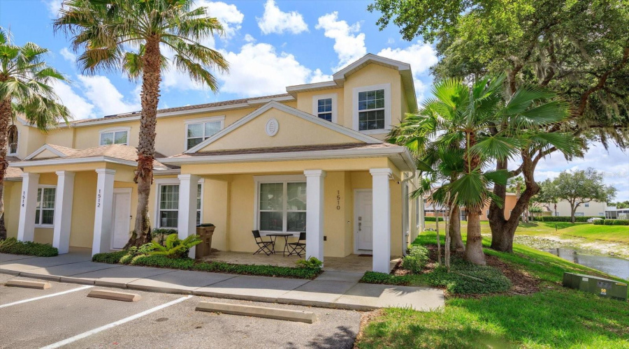 Welcoming Exterior View Of This Corner-Unit Townhouse, Ideally Positioned Beside A Tranquil Pond And Surrounded By Palm Trees.