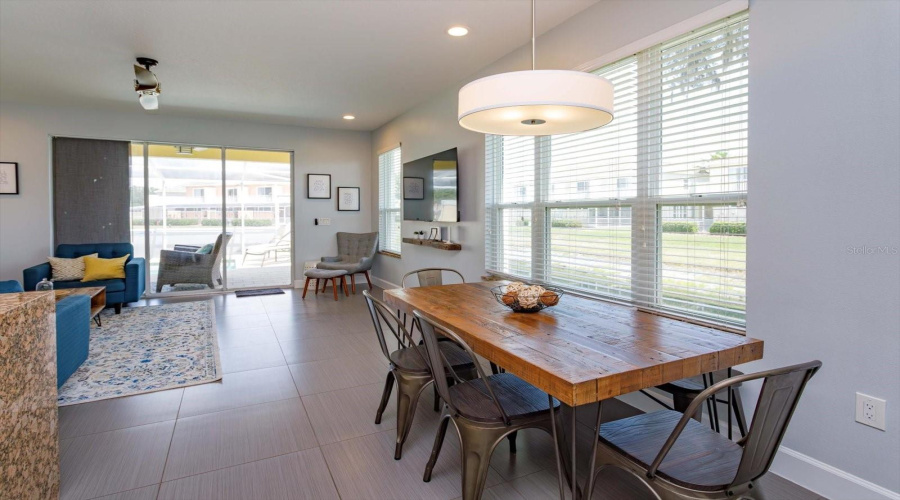Bright And Open Dining Area Featuring Oversized Windows, Natural Light, And Direct Access To The Screened-In Private Pool Area.
