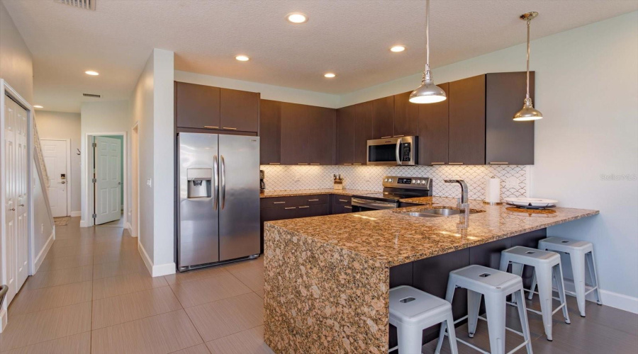 Kitchen Featuring Spacious Granite Countertops, Modern Appliances, And Ample Workspace.