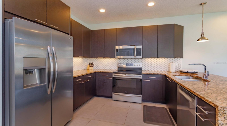 Modern Kitchen With Granite Countertops, Stainless Steel Appliances, Upgraded Cabinetry, And Breakfast Bar Seating.