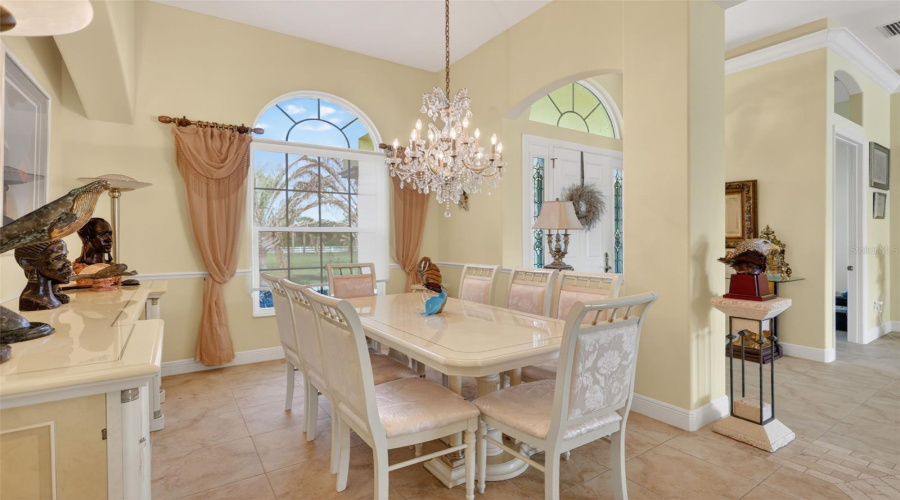 Elegant Formal Dining Room Featuring Soaring Ceilings, Crown Molding, Abundant Natural Light, And A Statement Chandelier For Memorable Gatherings And Entertaining.