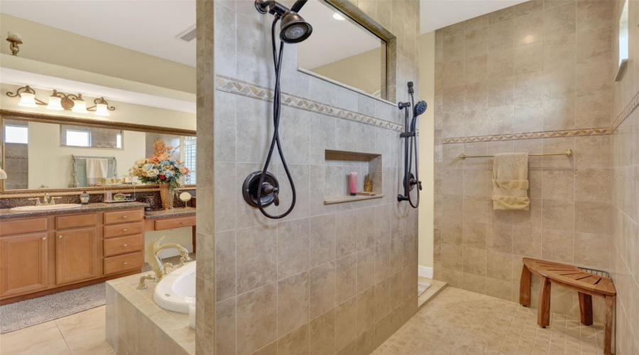 The Luxurious Primary Bath Showcases A Walk-Through Tiled Shower With Dual Shower Heads, Built-In Niches, And A Spacious Spa-Like Design.