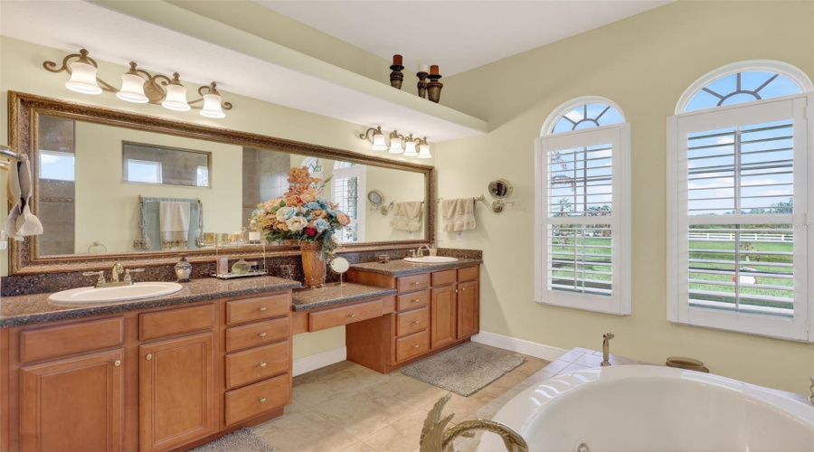 The Elegant Primary Bath Features Dual Vanities With Abundant Storage, A Dedicated Seated Vanity Area, And Beautiful Natural Light From Oversized Windows.