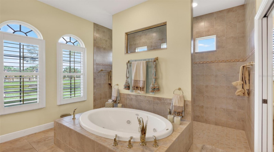 Designed With Relaxation In Mind, The Spa-Inspired Primary Bath Offers A Soaking Tub, Expansive Walk-Through Shower, And Peaceful Views Of The Surrounding Property.