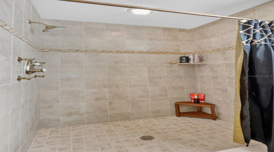 The Spacious Walk-In Shower Features Floor-To-Ceiling Tile, Decorative Accents, And A Clean, Timeless Design.