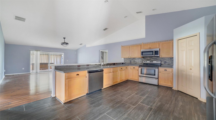 The Heart Of The Home Is A Spacious Kitchen With Vaulted Ceilings, Wood Cabinetry, Stone Countertops, A Breakfast Bar, And A Generous Pantry, All Flowing Seamlessly Into The Open Family Room.
