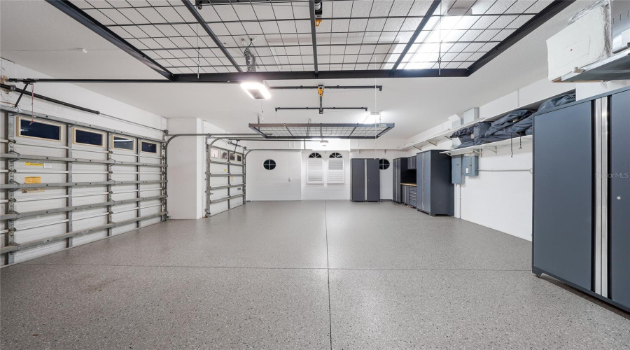 A Side-Load Oversized And Deep 3 Car Garage With New Epoxy Flooring, Ceiling Racks And Cabinetry