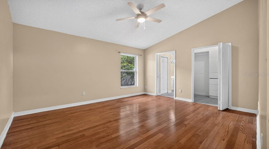 Spacious Primary Bedroom With Vaulted Ceilings And Wood-Look Flooring.