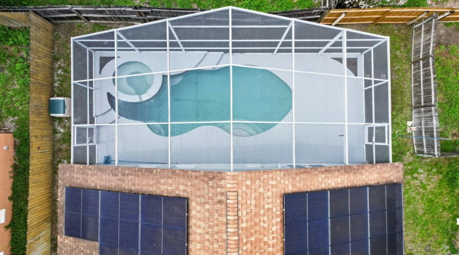 Aerial View Of The Screen-Enclosed Pool, Spa, And Solar Panels.