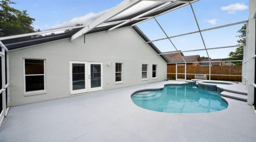 Screen-Enclosed Pool And Spa With An Expansive Pool Deck, An Ideal For Outdoor Enjoyment.