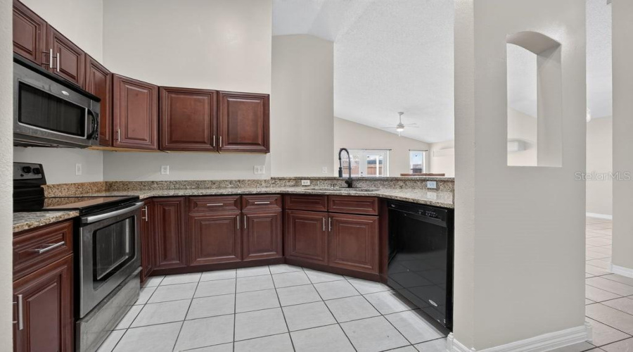 Kitchen With Wood Cabinetry, Stainless Steel Appliances, And A Breakfast Bar.
