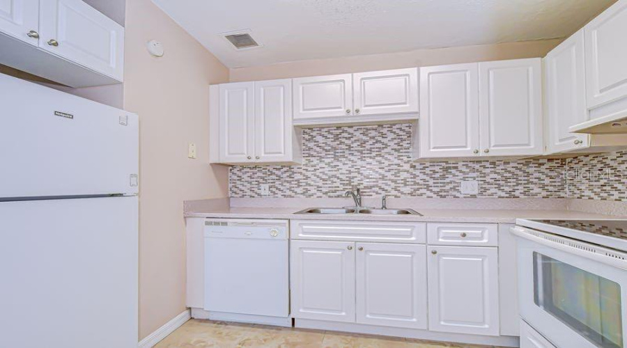 Fully Equipped Kitchen Featuring White Cabinets, Appliances, Beautiful Backsplash And Countertops