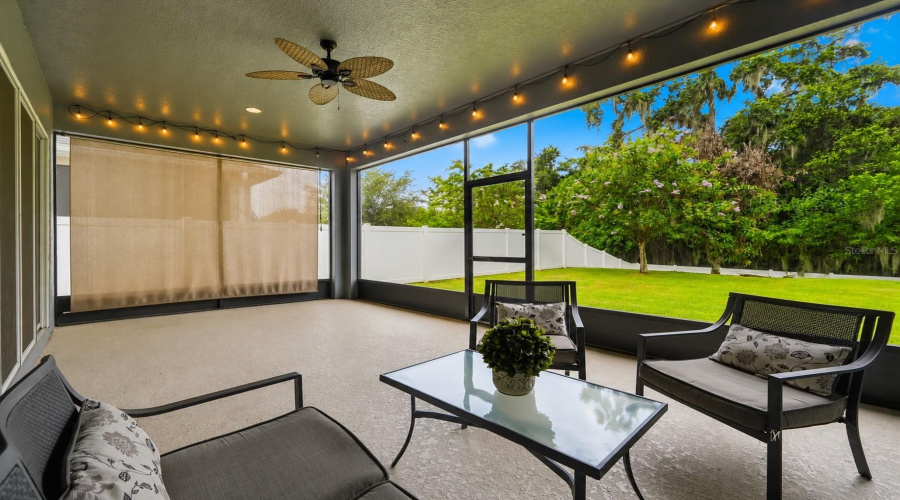 The Expansive Screened Lanai With A Retractable Privacy Shade Invites Effortless Florida Living, From Peaceful Mornings Overlooking The Lush Backyard To Relaxed Evenings Entertaining Under The Glow Of String Lights.