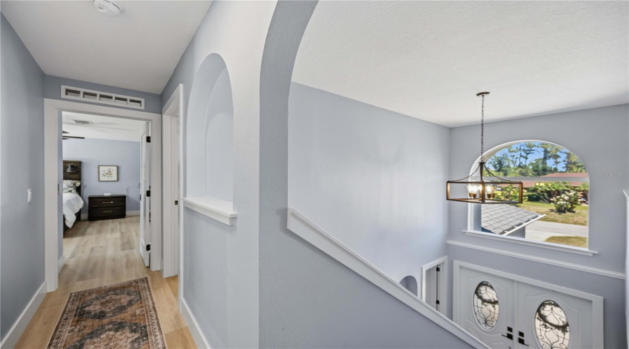 Upstairs Hallway Showing Vaulted Ceiling From The Foyer And Entry To Primary Bedroom