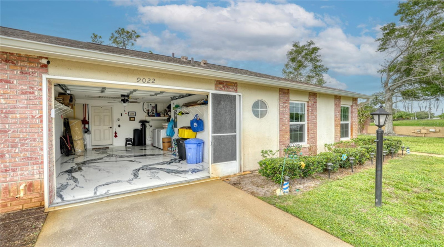 Attached One-Car Garage Featuring Epoxy Flooring, Built-In Shelving, And Additional Storage Space.