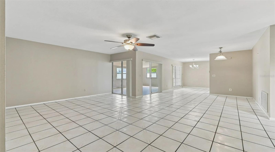 Expansive Tiled Flooring Extending Throughout, Ceiling Fan With Integrated Lighting, Built-In Display Cabinetry, And Sliding Glass Doors