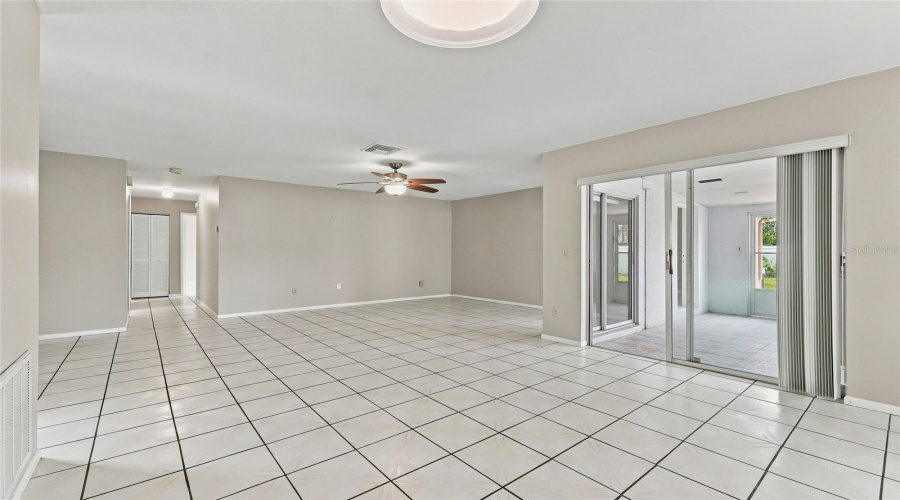 Spacious Interior With Tiled Flooring, Neutral Wall Tones, Ceiling Fan, And Sliding Glass Doors