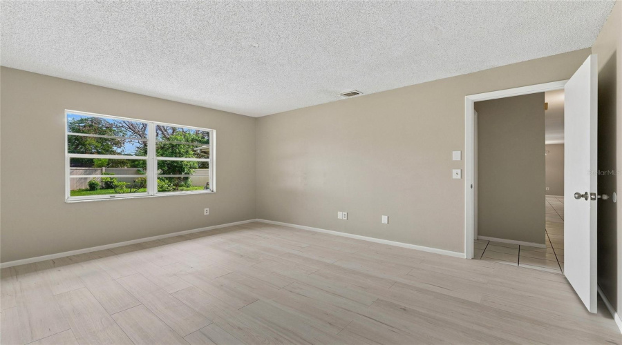 Light-Toned Wood-Finish Flooring, Neutral Wall Paint, And A Large Window Providing Natural Light