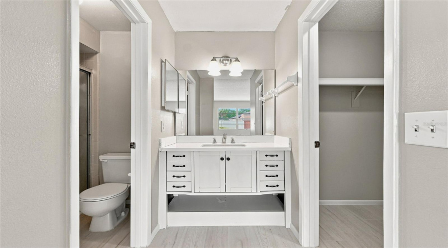 White Vanity With A Single Basin, Brushed Nickel Faucet, And Black Hardware