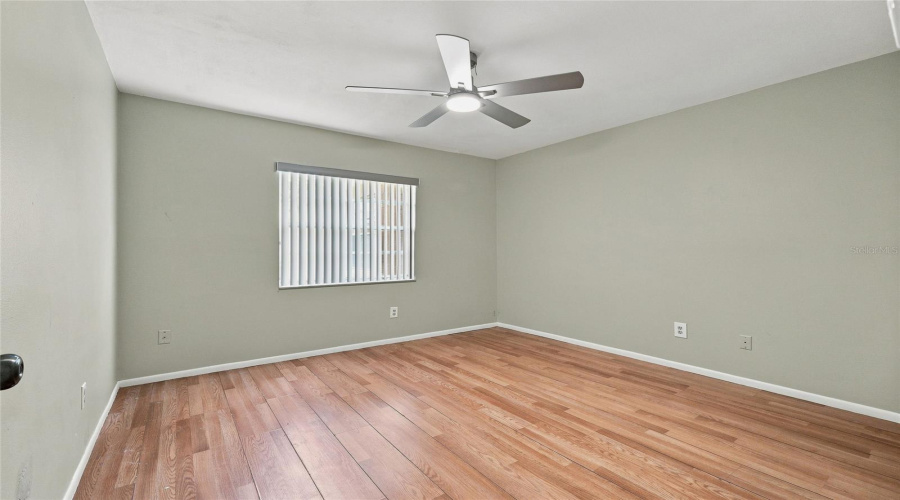 Wood-Finish Flooring, Neutral Wall Tones, And A Ceiling Fan With Integrated Lighting