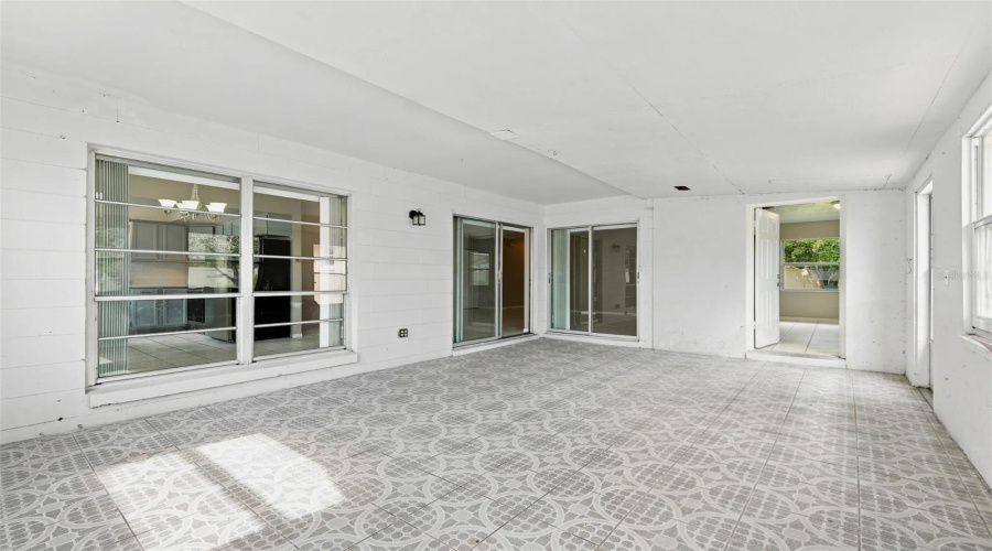 Enclosed Patio With Patterned Tile Flooring, Multiple Sliding Glass Doors, And Large Windows